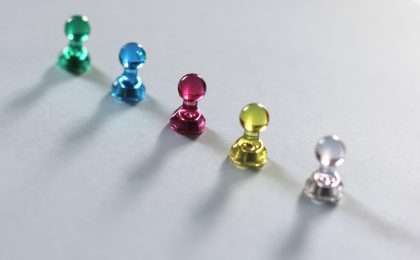 少女前线2相关资料卡片在桌面上按年份排列，编辑用铅笔在时间轴手稿上标注待核记号，纸面边缘泛着米色暖光